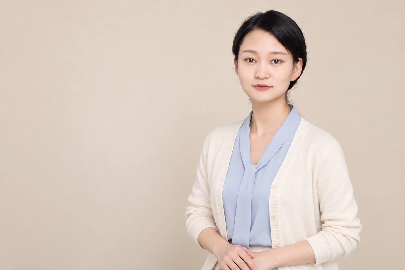 女士穿淺色外套在暖米色背景前拍攝的半身形象照