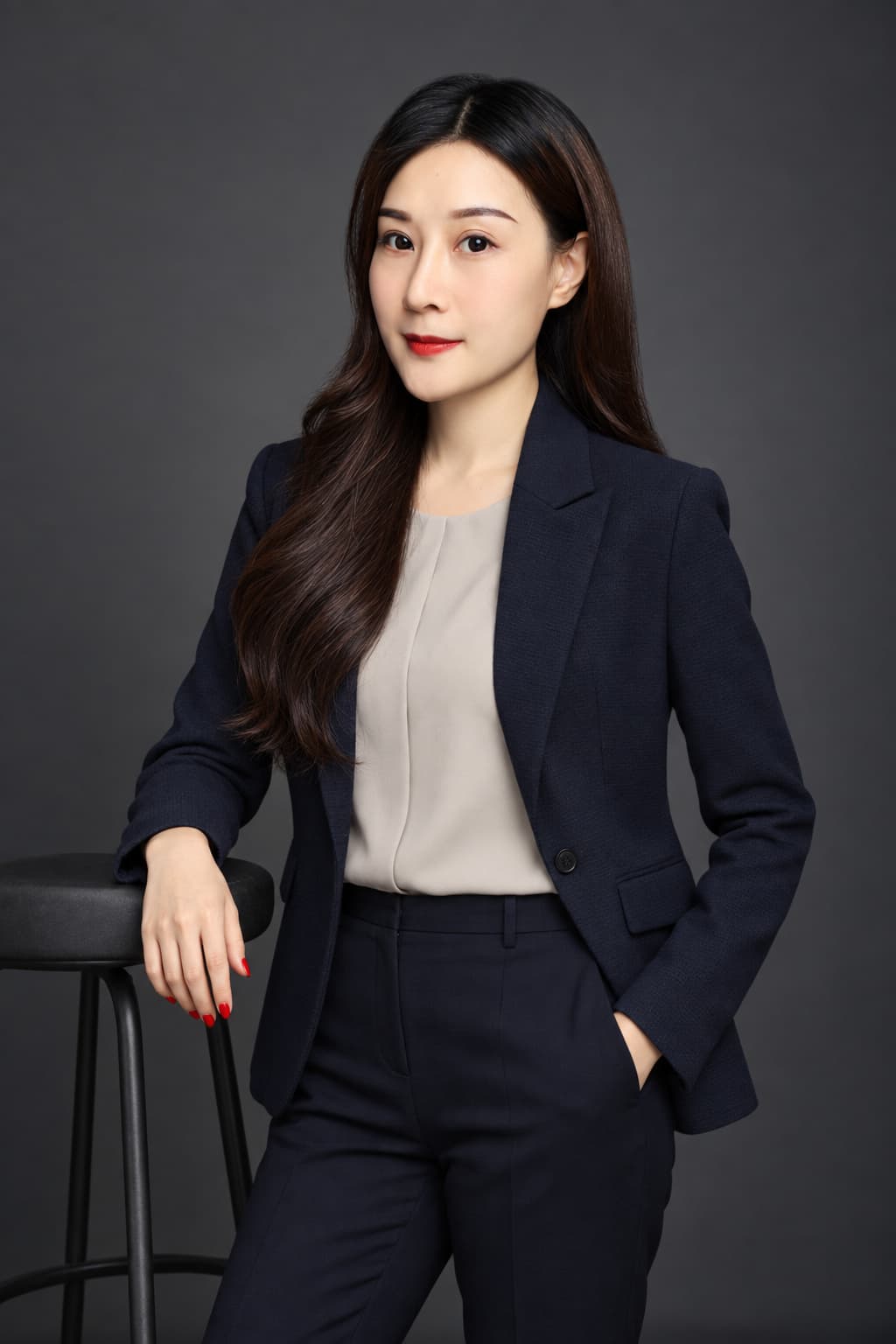 Woman in a dark suit, charcoal backdrop