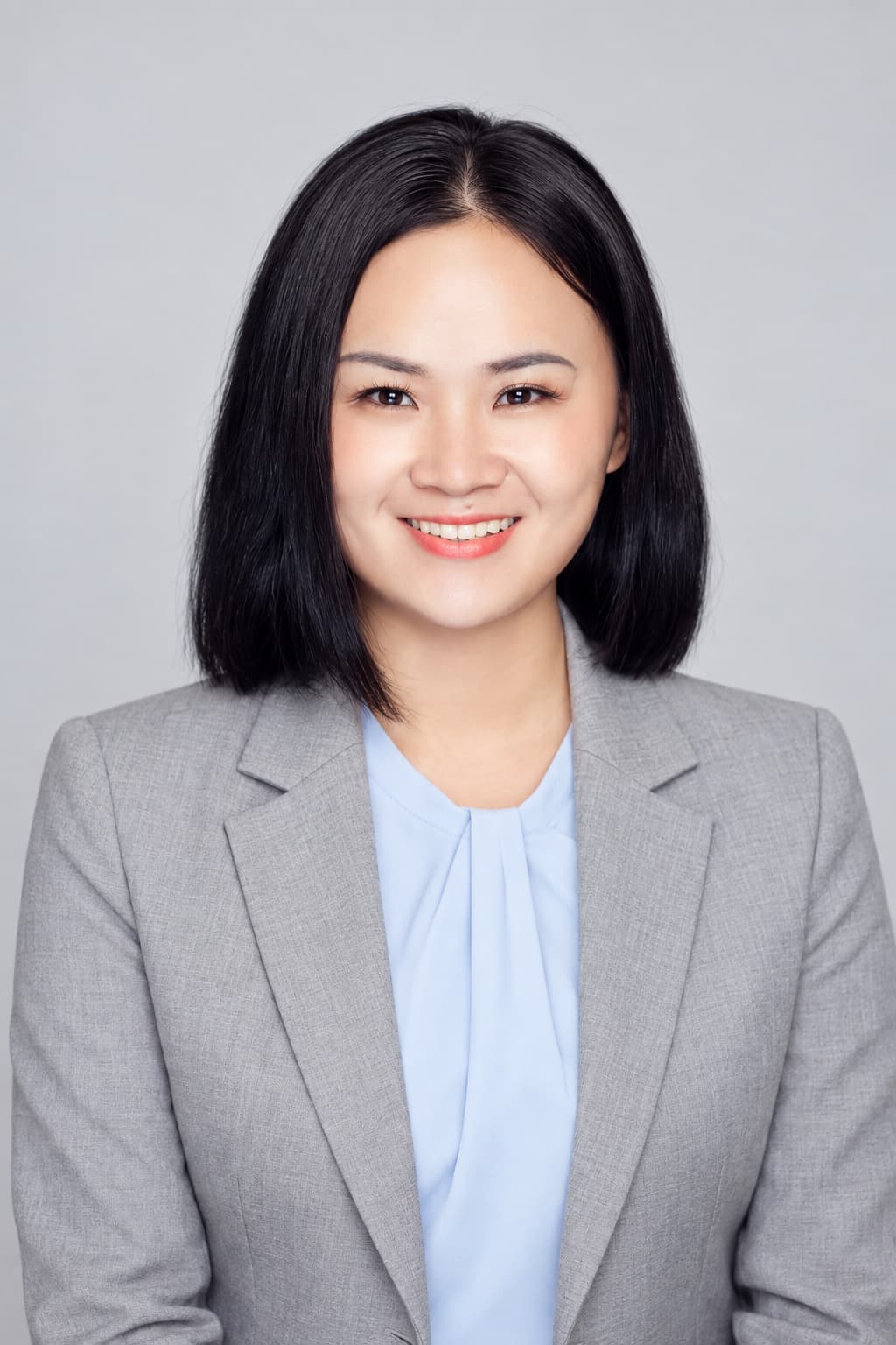 Female colleague in a light gray blazer, light gray backdrop