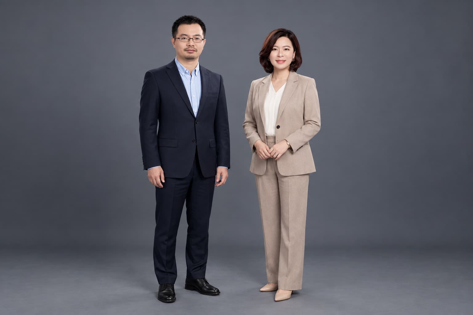 Two executives standing full length, charcoal backdrop