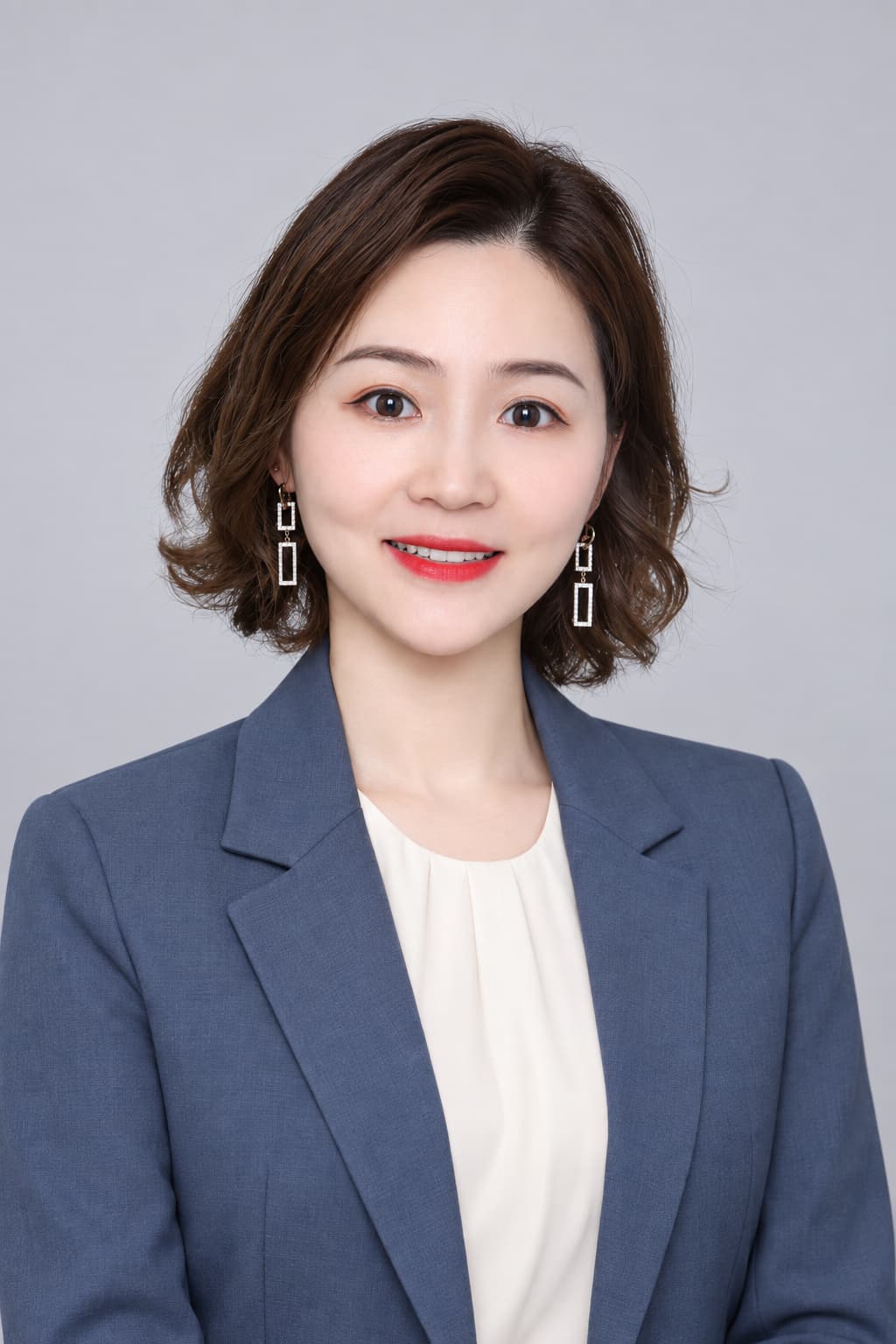 Female colleague in a blue blazer, light gray backdrop